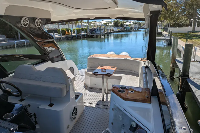Slide: The Image of 2023 NX Boats 340 Sport Coupe interior with luxurious seating and scenic waterfront view. - 37