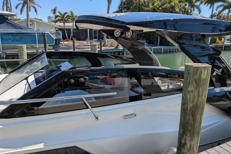 Slide: The Image of 2023 NX Boats 340 Sport Coupe docked by a waterfront, showcasing sleek design. - 46