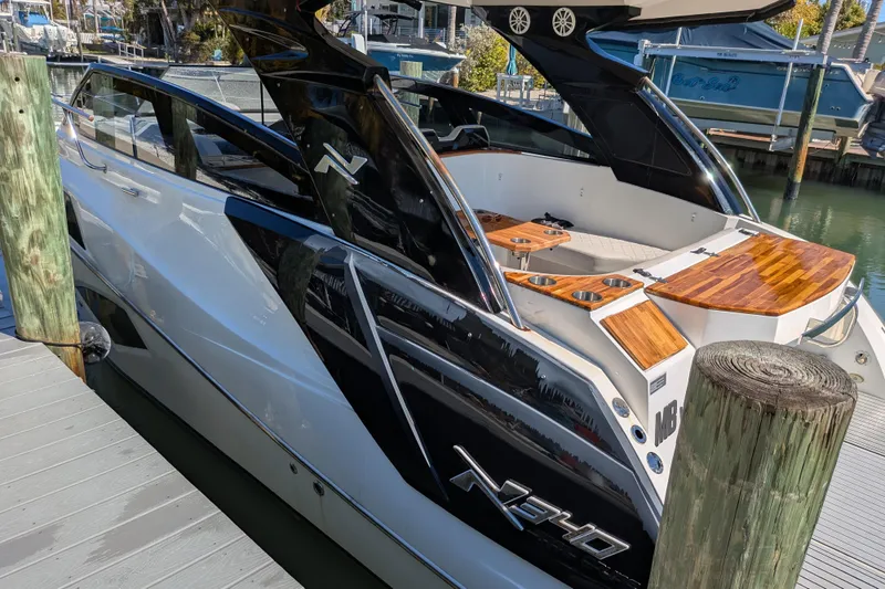 Slide: The Image of 2023 NX Boats 340 Sport Coupe docked, showcasing sleek design and luxurious wood accents. - 49