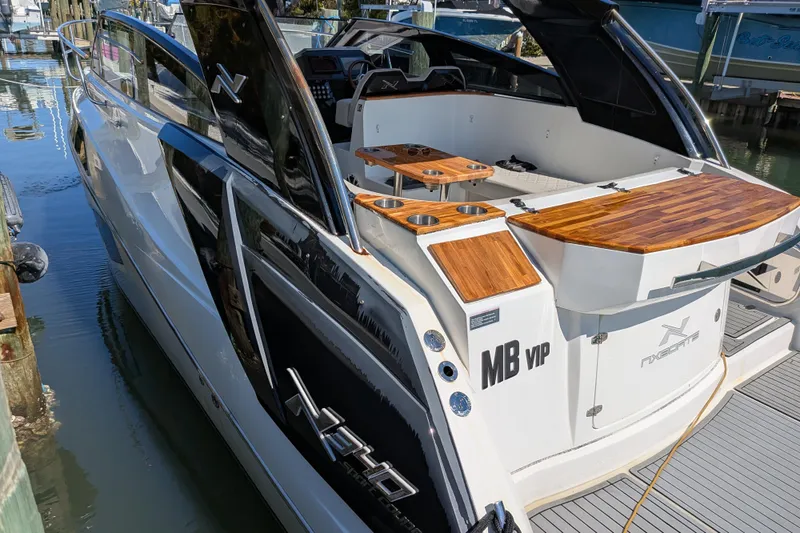 Slide: The Image of 2023 NX Boats 340 Sport Coupe docked, showcasing sleek design and wooden accents. - 51