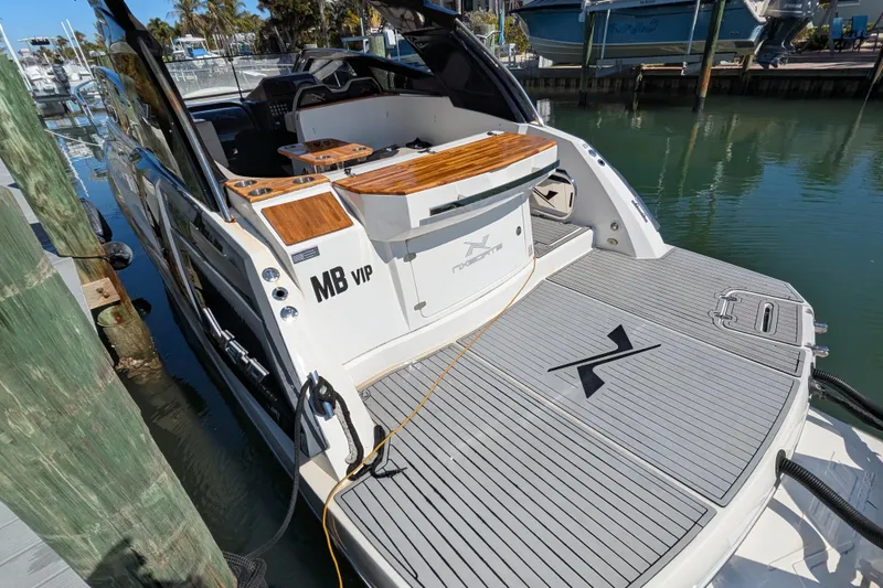 Slide: The Image of 2023 NX Boats 340 Sport Coupe docked, showcasing sleek design and spacious deck. - 54