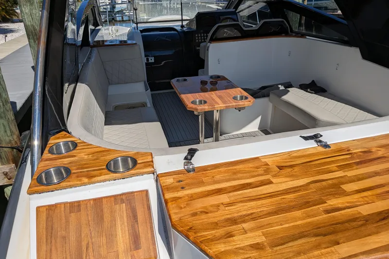 Slide: The Image of 2023 NX Boats 340 Sport Coupe interior with wood accents and seating area. - 58