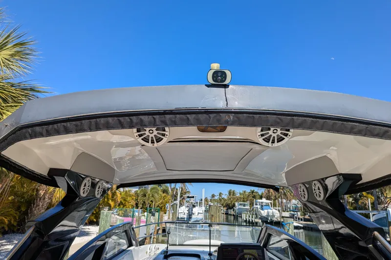 Slide: The Image of 2023 NX Boats 340 Sport Coupe with speakers, docked under clear blue sky. - 61