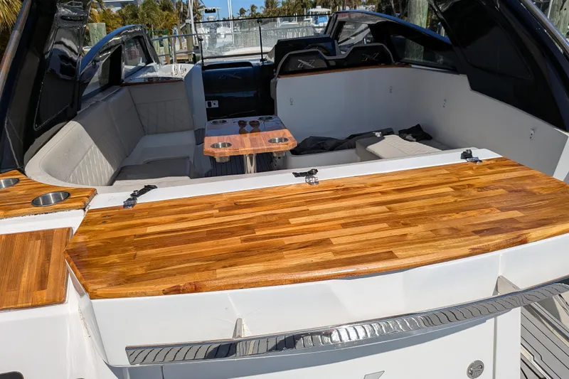 Slide: The Image of 2023 NX Boats 340 Sport Coupe interior with wooden accents and seating area. - 62