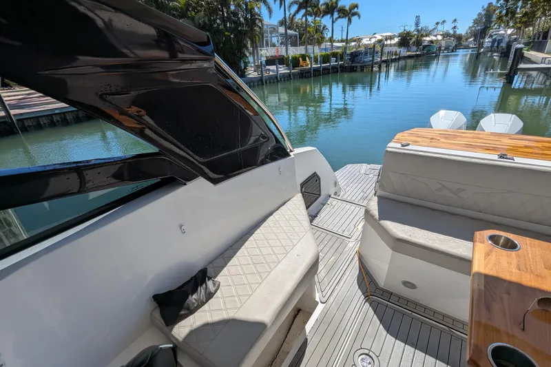 Slide: The Image of 2023 NX Boats 340 Sport Coupe interior with seating, table, and scenic waterfront view. - 69