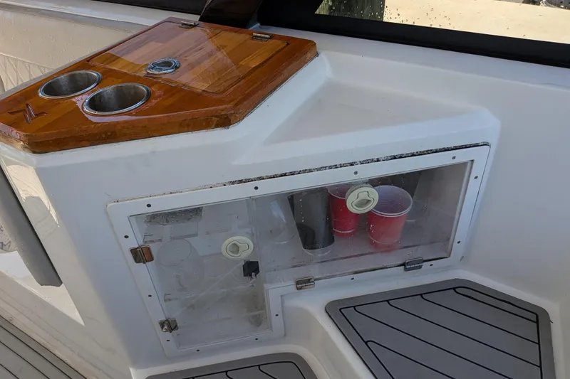 Slide: The Image of 2023 NX Boats 340 Sport Coupe interior with cup holders and storage compartment. - 73