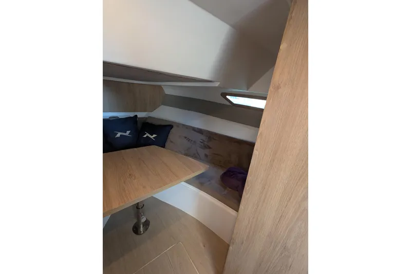 Slide: The Image of 2023 NX Boats 340 Sport Coupe interior cabin with wooden table and seating area. - 78