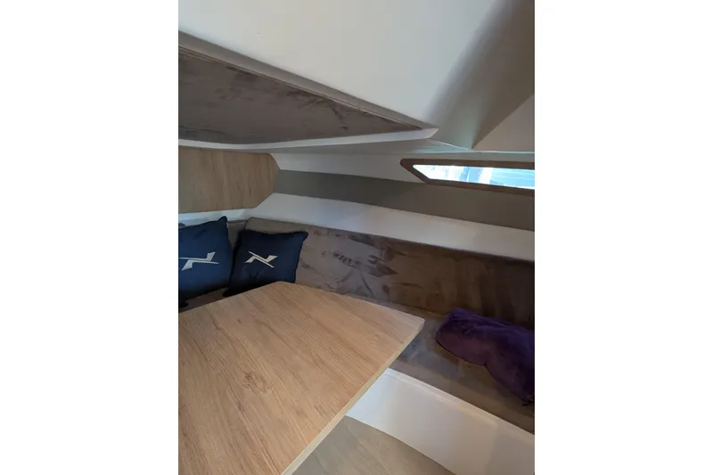 Slide: The Image of Interior of 2023 NX Boats 340 Sport Coupe with wooden table and cushions. - 80