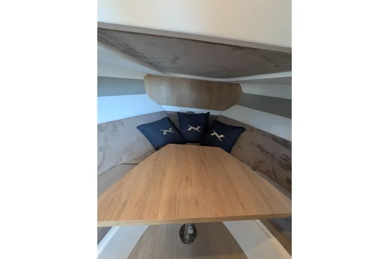 Slide: The Image of Interior of 2023 NX Boats 340 Sport Coupe with wooden table and cushions. - 81