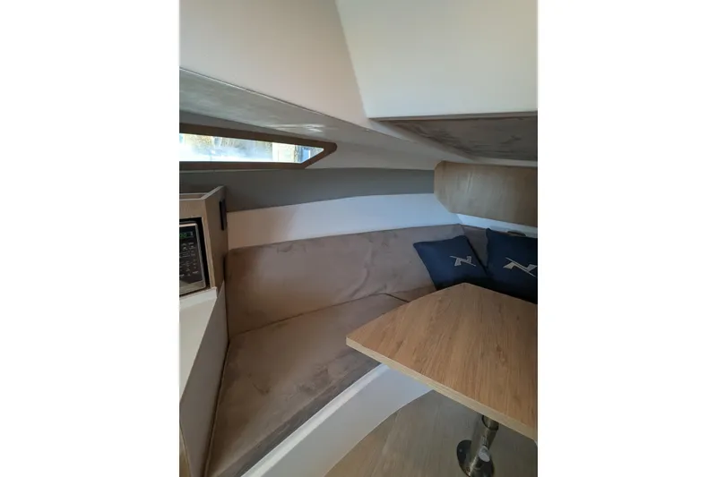 Slide: The Image of 2023 NX Boats 340 Sport Coupe interior with cozy seating and wooden table. - 82