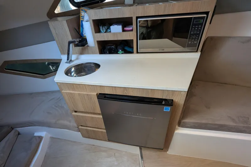 Slide: The Image of Compact kitchenette in 2023 NX Boats 340 Sport Coupe with sink, microwave, and fridge. - 84