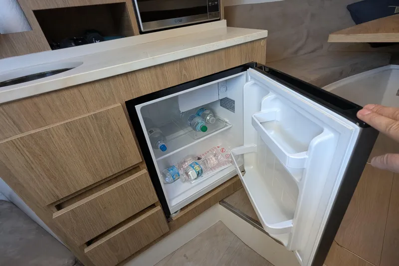 Slide: The Image of Compact fridge in 2023 NX Boats 340 Sport Coupe, stocked with water bottles. - 86