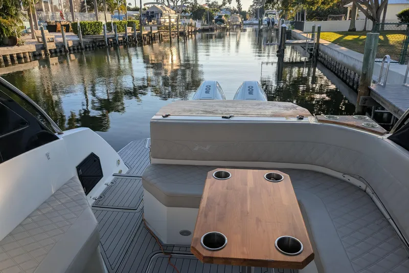 Slide: The Image of 2023 NX Boats 340 Sport Coupe interior with wooden table and waterfront view. - 9