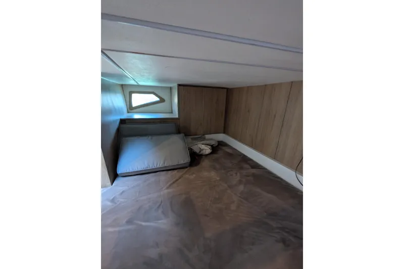 Slide: The Image of 2023 NX Boats 340 Sport Coupe cabin interior with wooden paneling and compact sleeping area. - 94