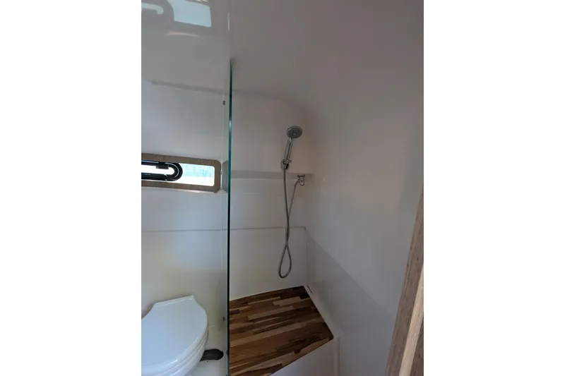 Slide: The Image of Bathroom interior of 2023 NX Boats 340 Sport Coupe with shower and wooden accents. - 96