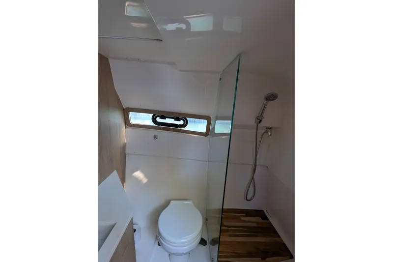 Slide: The Image of 2023 NX Boats 340 Sport Coupe bathroom with shower, toilet, and window. - 97