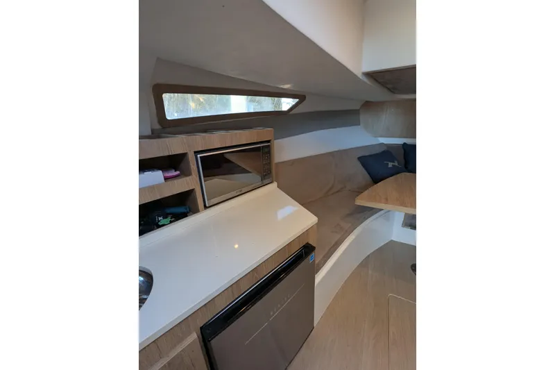 Slide: The Image of 2023 NX Boats 340 Sport Coupe interior with kitchenette and seating area. - 99