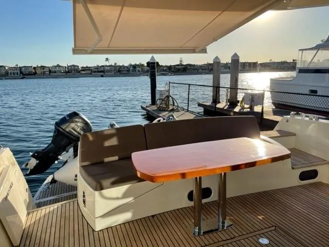 Slide: The Image of Prestige 500 yacht deck, 2017 model, with seating and table overlooking a marina at sunset. - 10