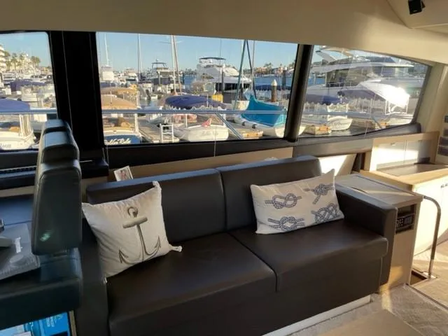 Slide: The Image of Luxurious 2017 Prestige 500 yacht interior with marina view, featuring elegant seating and nautical-themed cushions. - 20