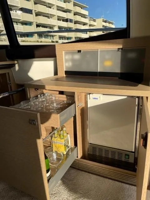 Slide: The Image of Luxurious 2017 Prestige 500 yacht interior with minibar and glassware, overlooking modern buildings. - 37