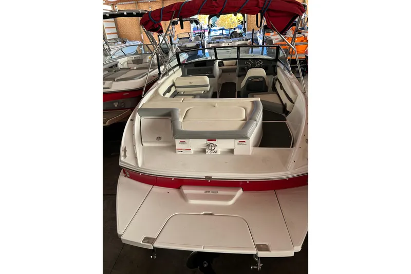 Slide: The Image of 2021 Cobalt CS22 boat with red canopy and spacious seating in a showroom. - 5