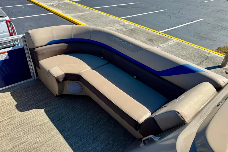 Slide: The Image of 2023 Bennington 23 SX boat interior with beige and blue seating, parked on pavement. - 28