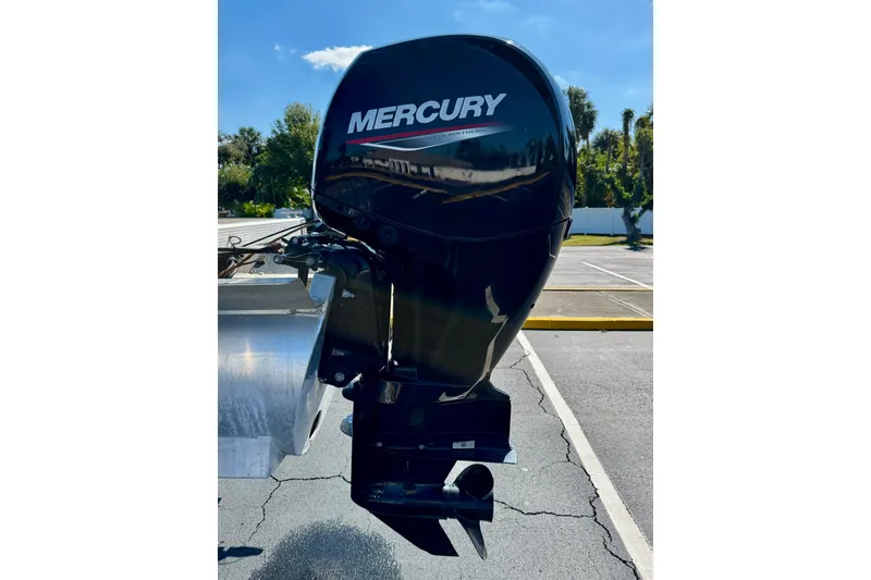 Slide: The Image of 2023 Bennington 23 SX with Mercury outboard motor in a sunny parking lot. - 31