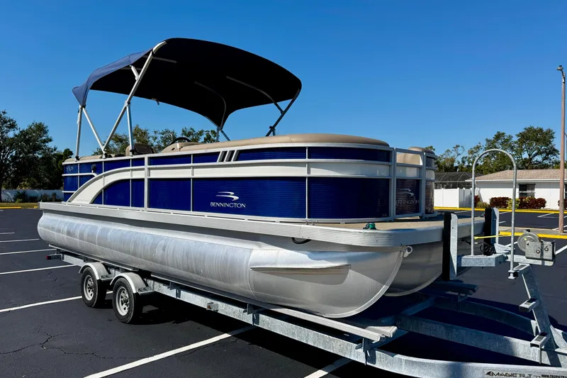 Slide: The Image of 2023 Bennington 23 SX pontoon boat on trailer, parked in sunny lot. - 4