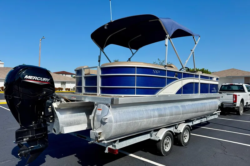 Slide: The Image of 2023 Bennington 23 SX pontoon boat with Mercury engine on trailer, parked outdoors. - 5
