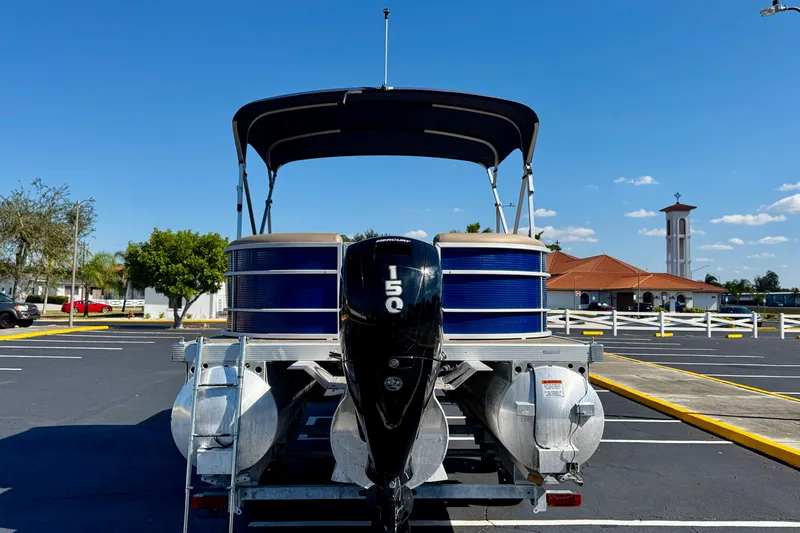 Slide: The Image of 2023 Bennington 23 SX pontoon boat with 150 HP engine in a parking lot. - 6
