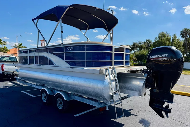 Slide: The Image of 2023 Bennington 23 SX pontoon boat with Mercury outboard motor on a trailer. - 7