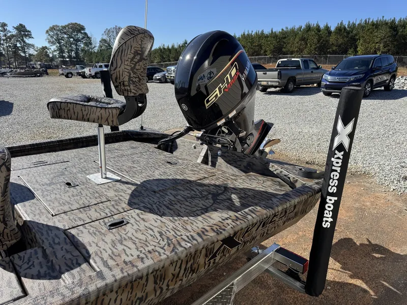 Slide: The Image of 2026 Xpress XP180 boat with camo seats and Yamaha motor in a parking lot. - 9