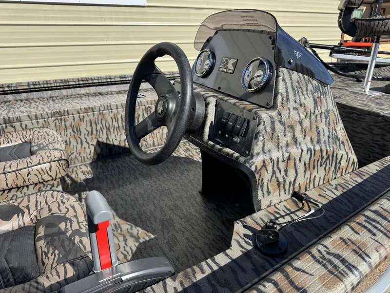 Slide: The Image of 2026 Xpress XP180 boat interior with camouflage design, featuring steering wheel and dashboard controls. - 6