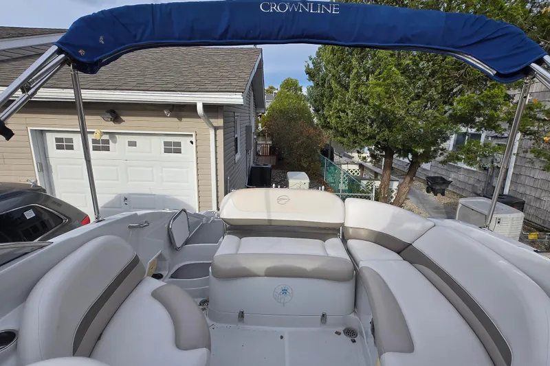 Slide: The Image of 2012 Crownline Eclipse E4 boat interior with seating and canopy, parked near a garage. - 12