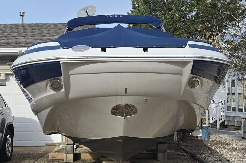Slide: The Image of 2012 Crownline Eclipse E4 boat on blocks, parked near a house and car. - 9