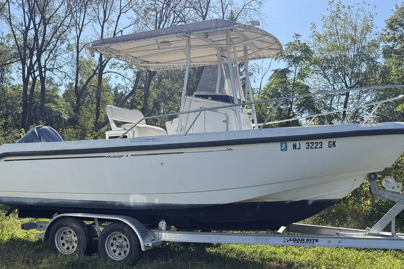 The Image of 1999 Boston Whaler 21 Outrage boat on trailer in wooded area. - 0