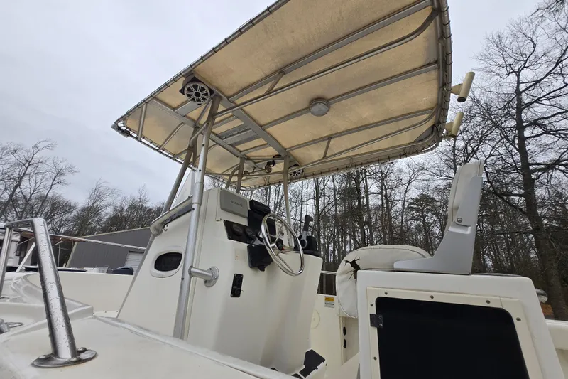 Slide: The Image of 1999 Boston Whaler 21 Outrage boat with canopy and steering console, surrounded by trees. - 21