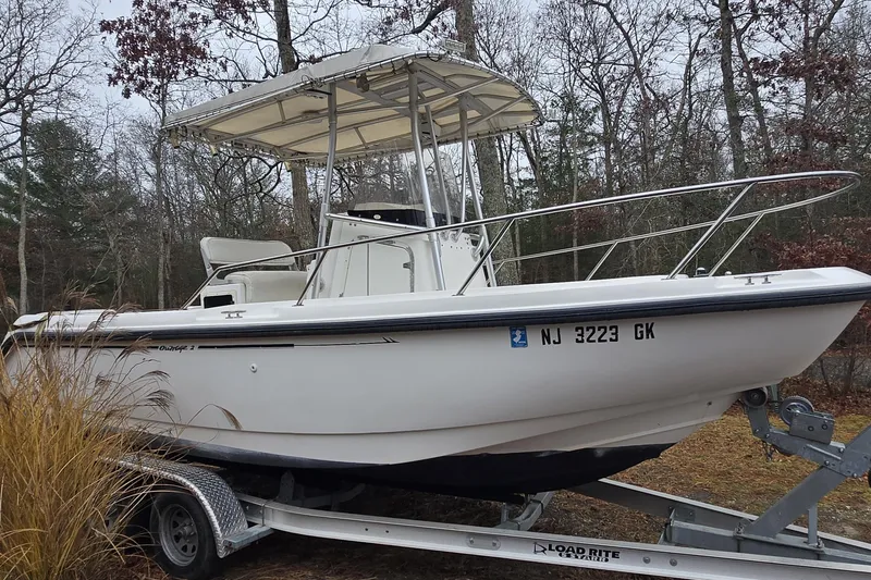 Slide: The Image of 1999 Boston Whaler 21 Outrage boat on trailer in wooded area. - 25