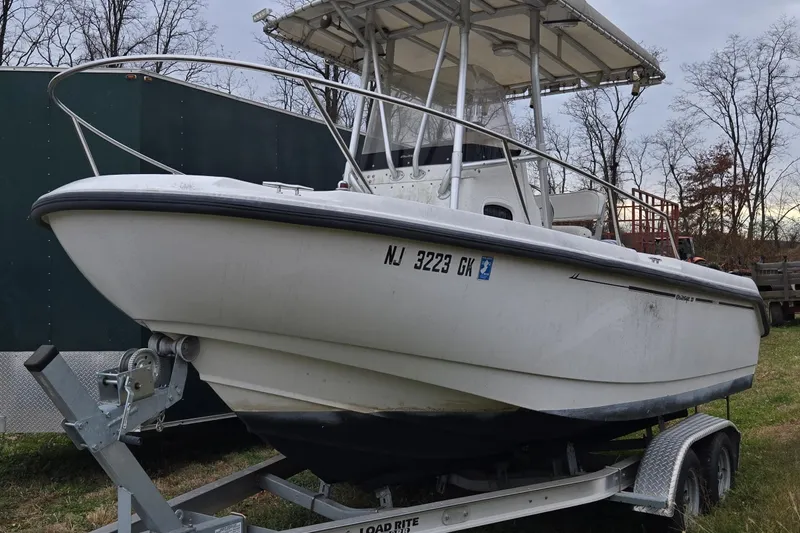 Slide: The Image of 1999 Boston Whaler 21 Outrage boat on trailer, parked outdoors in wooded area. - 8