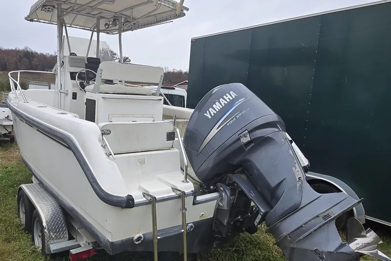Slide: The Image of 1999 Boston Whaler 21 Outrage boat with canopy, parked in wooded area. - 9