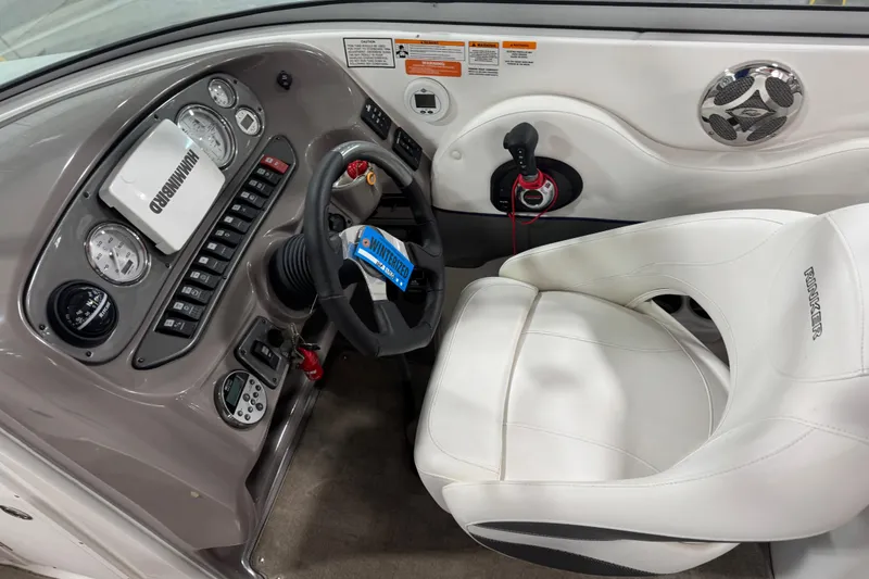 Slide: The Image of 2010 Rinker 296 Captiva Bowrider cockpit with steering wheel, gauges, and white captain's chair. - 7