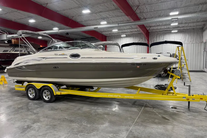 The Image of 2005 Sea Ray 240 Sundeck boat on yellow trailer in indoor showroom. - 1