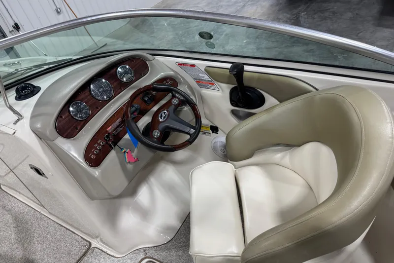 Slide: The Image of 2005 Sea Ray 240 Sundeck helm with steering wheel and gauges, beige seating. - 11