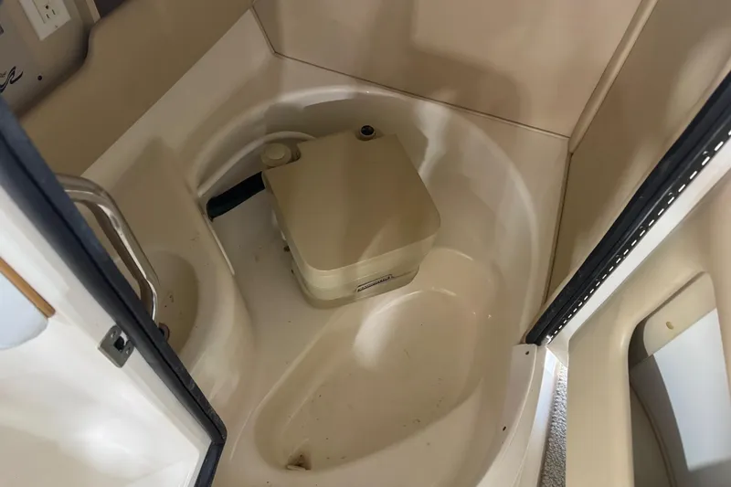Slide: The Image of Interior of 1998 Sea Ray 280 Bow Rider with portable toilet in compact bathroom space. - 11