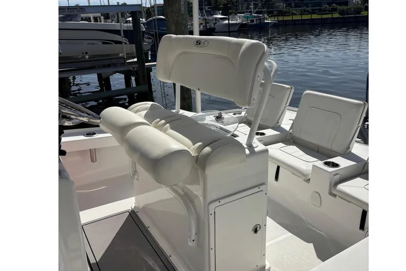 Slide: The Image of 2022 Sea Hunt BX 22 Pro boat interior with seating and storage, docked by the water. - 9