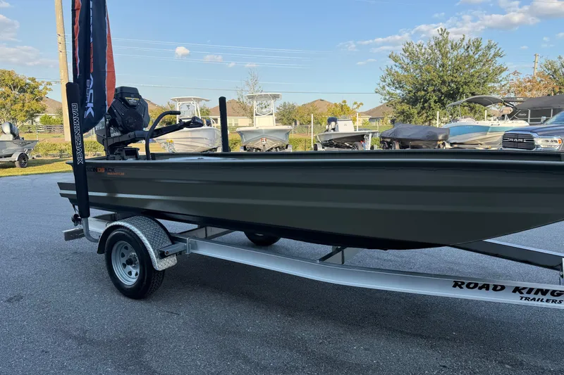 Slide: The Image of 2025 Diamondback 1754 MUD RATTLER boat on Road King trailer, parked outdoors. - 4