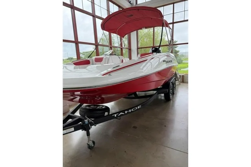 The Image of 2026 Tahoe 1950 boat with red and white design, parked indoors on a trailer. - 0