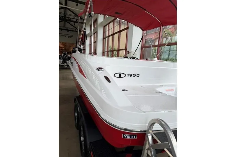 Slide: The Image of 2026 Tahoe 1950 boat with red canopy, displayed indoors. - 2