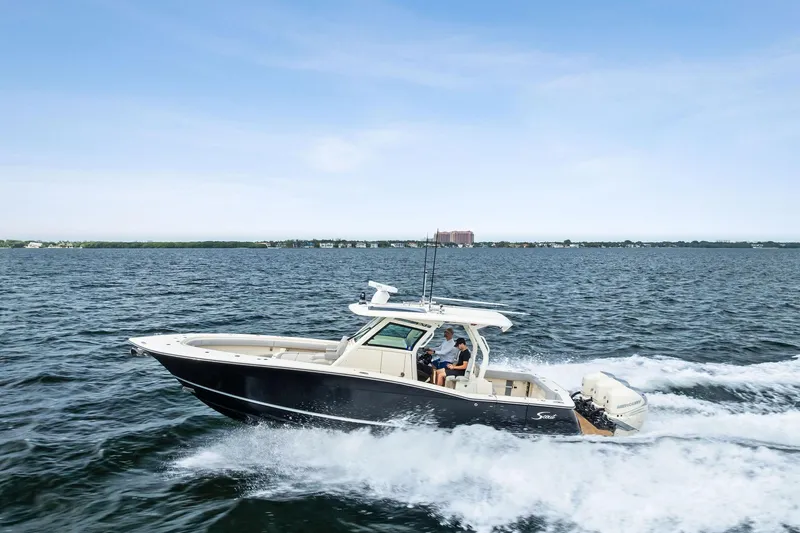 The Image of 2020 Scout 355 LXF boat cruising on open water under a clear sky. - 1