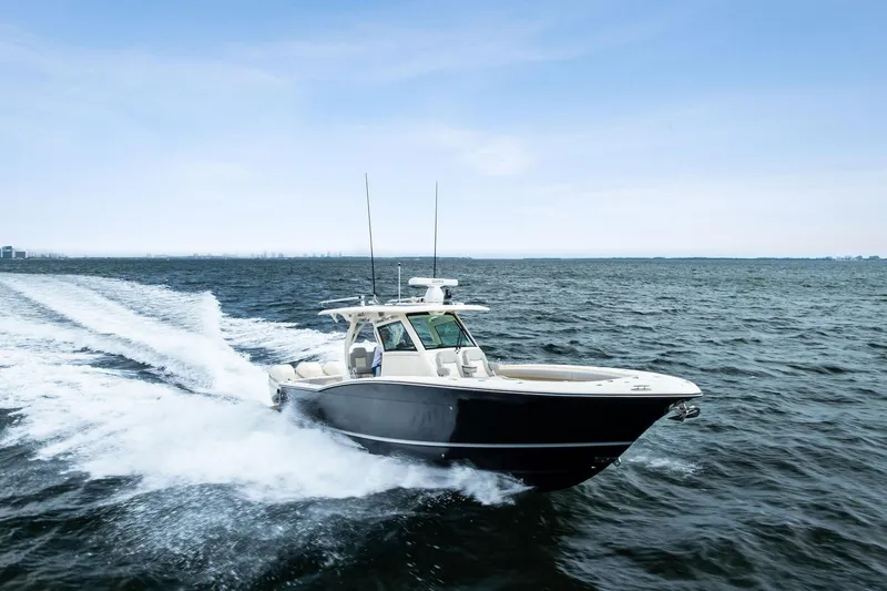 Slide: The Image of 2020 Scout 355 LXF boat cruising on open water under clear skies. - 11